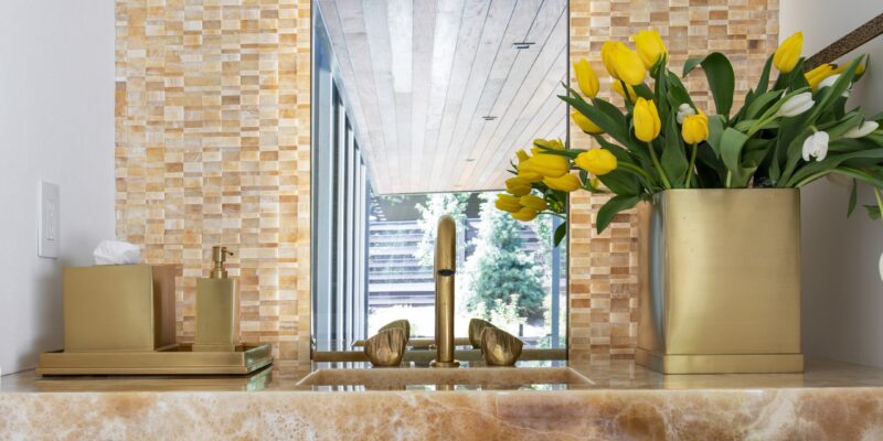 Luxurious, organic bathroom with calcite vanity, a tall and slim mirror, gold accents, and beautiful, clean white walls.