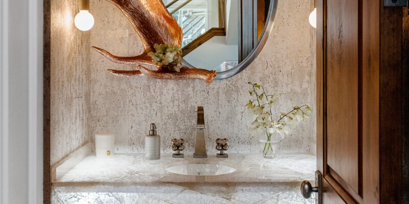 Utah mountain home bathroom with a custom vanity, backlights, a real antler, and sculptural sconce lights.